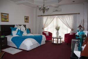a bedroom with a bed and two red chairs at Hotel Mount Maluti - Lesotho in Mohales Hoek