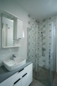 ein weißes Bad mit einem Waschbecken und einer Dusche in der Unterkunft Studio apartman Golden Lux in Pale