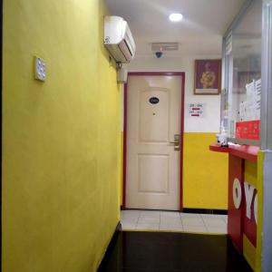 um corredor com uma porta branca e paredes amarelas em 1st Inn Hotel Glenmarie em Shah Alam