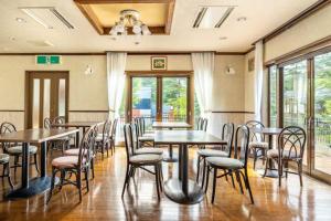 a dining room with tables and chairs and windows at Seventh Heaven Hakuba in Hakuba