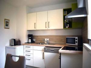 cocina con armarios blancos, fregadero y microondas en Bögi's Ferienwohnung, en Leipheim