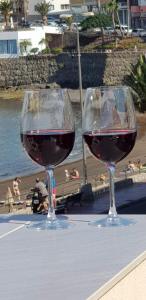 twee glazen wijn zittend op een tafel bij het strand bij 3Arguineguin terrasse apart next to beach in Arguineguín
