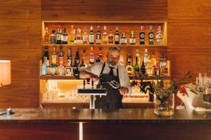 Um homem atrás de um bar com garrafas de álcool. em Boutique Hotel & Villa AUERSPERG em Salzburgo