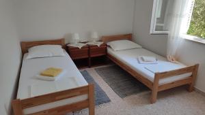 two twin beds in a room with a window at Apartmani Vinko Bol in Bol