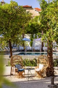 three chairs and a table in front of a pool at Hotel Supetar in Cavtat