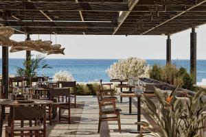 a restaurant with tables and chairs with the ocean in the background at Elissa Adults-Only Lifestyle Beach Resort in Kallithea Rhodes