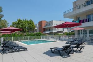 a group of chairs and umbrellas next to a pool at Comfort Aparthotel Cannes Mandelieu in Mandelieu-la-Napoule
