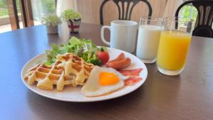 a plate of breakfast food with waffles and salad and orange juice at Seventh Heaven Hakuba in Hakuba