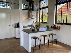 a kitchen with a counter and stools in a room at Kerkje van Peins in Peins +17 photos