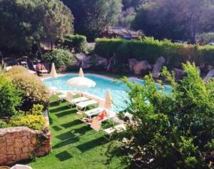 uma piscina com espreguiçadeiras e um guarda-sol em green park cala di volpe em Abbiadori