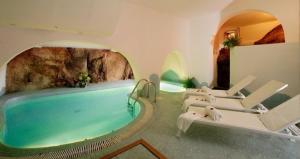 Abbiadori的住宿－green park cala di volpe，一个带椅子和岩石墙的游泳池的房间