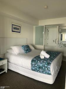 um quarto com uma cama grande com lençóis azuis e brancos em Just Perfect Apartment with Ocean Views em Caloundra