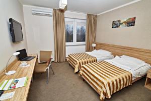Habitación de hotel con 2 camas y escritorio en MPM Sport HOTEL en Radomsko