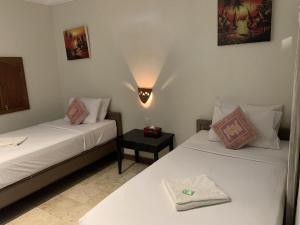 a room with two beds and a nightstand between them at Hotel Sanur Indah in Sanur