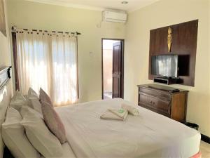 a bedroom with a white bed and a television at Hotel Sanur Indah in Sanur