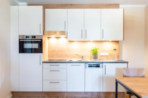 a kitchen with white cabinets and a wooden table at Ostsee Apartmenthotel in Graal-Müritz