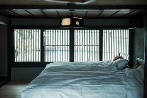 ein Bett in einem Schlafzimmer mit einem großen Fenster in der Unterkunft Oito 美しい街並みに佇む喫茶と宿 in Tamba-sasayama