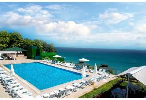 a swimming pool with chairs and umbrellas and the ocean at Westport Istanbul Resort & Spa Hotel in Silivri