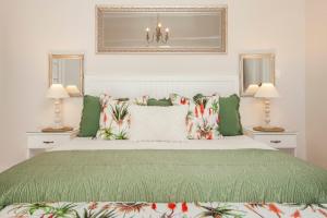 ein Schlafzimmer mit einem grünen und weißen Bett mit Kissen in der Unterkunft Cliff Cottage Hermanus in Hermanus
