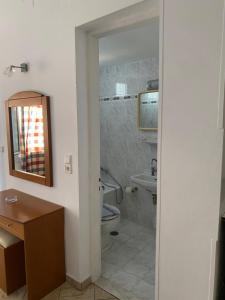 a bathroom with a toilet and a sink and a mirror at Hotel Damo in Pythagoreio