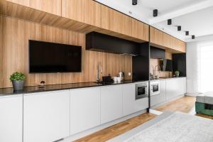 a kitchen with white cabinets and a flat screen tv at Downtown Apartments Waterlane Island - Riverview Pool, SPA & Gym in Gdańsk
