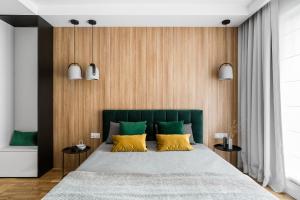 sypialnia z łóżkiem z zielonymi i żółtymi poduszkami w obiekcie Downtown Apartments Waterlane Island - Riverview Pool, SPA & Gym w Gdańsku