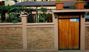 uma parede de tijolos com uma porta de madeira em frente a um edifício em Guest House - Avlabari em Tbilisi