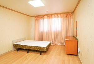 Koresco Chiak Mountain Condominium في Hoengsong: غرفة نوم بسرير ونافذة وخزانة