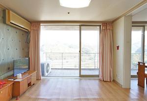 Koresco Chiak Mountain Condominium في Hoengsong: غرفة معيشة مع باب زجاجي منزلق كبير