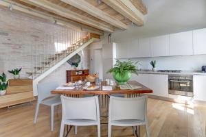 Villa Vetta Marina - My Extra Home في سيرولو: مطبخ وغرفة طعام مع طاولة وكراسي خشبية
