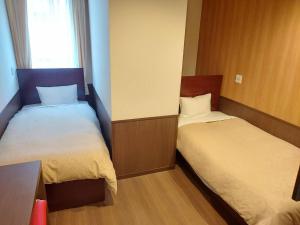 um pequeno quarto com 2 camas e uma janela em Hotel Ekichika Nagahoribashi em Osaka