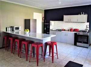 una cocina con encimera blanca y taburetes rojos en Summerville Place en Addo