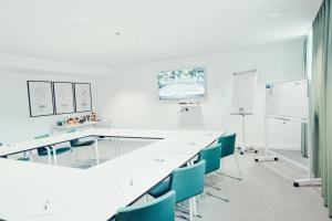 uma sala de aula com secretárias brancas e cadeiras azuis em Airbase Hotel em Kalsdorf bei Graz