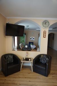 a living room with two black chairs and a tv at Pensiunea Elias in Cluj-Napoca