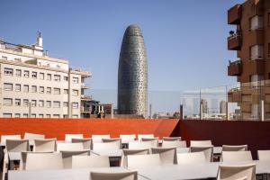 a group of white tables and chairs on a roof at Urbany Hostel Barcelona in Barcelona