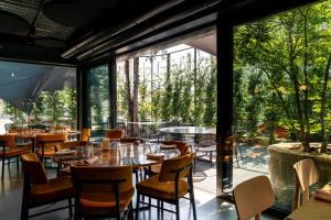 um restaurante com mesas e cadeiras e janelas grandes em Gustificio em Carmignano di Brenta