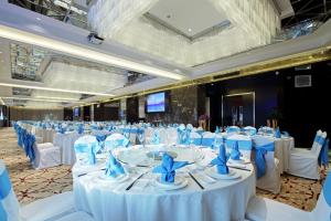 a banquet hall with white tables and blue chairs at Ramada Changzhou North Hotel in Changzhou