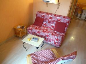 a living room with a red couch and a table at Studio Bagnères-de-Luchon, 1 pièce, 2 personnes - FR-1-313-120 in Luchon