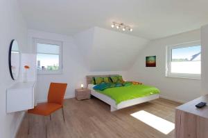 a white bedroom with a green bed and a chair at Ferienhaus Alt Sallenthin 10 B, "Sonne" in Neu Sallenthin