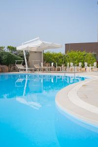 ein großer blauer Pool mit Stühlen und einem Sonnenschirm in der Unterkunft Mercure Olbia in Olbia