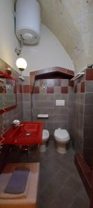 een badkamer met 2 toiletten en een rode wastafel bij Ambrosia Bed & Breakfast in Oria
