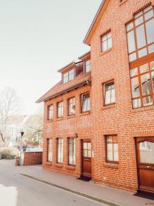 ein rotes Backsteingebäude mit Fenstern auf einer Straße in der Unterkunft Backsteinparadies in Lüneburg