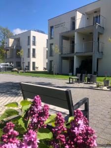 ławka w parku przed budynkiem z różowymi kwiatami w obiekcie Apartamenty Szmaragdowa 10 w mieście Mielno