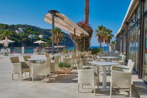 a patio with tables and chairs and the ocean at Grupotel Playa Camp de Mar - Adults Only in Camp de Mar