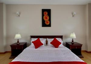 a bedroom with a large bed with red pillows at Fenesi Gardens Apartments in Nairobi