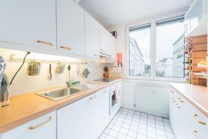 cocina con armarios blancos, fregadero y ventana en Apt Grohgasse nahe U Bahn en Viena