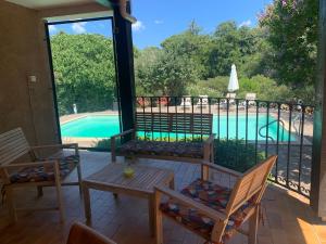 un patio con mesa, sillas y piscina en Villa dans un cadre verdoyant , piscine et jardin en Porto Vecchio