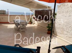einen Balkon eines Hauses mit einem Sonnenschirm und einem Tisch in der Unterkunft La vecchia Badessa a due passi dal mare in Macari