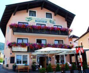 a building with a balcony with flowers and an umbrella at Gasthof Wildschönauer Bahnhof in Wörgl