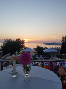 un vase de fleurs assis sur une table au coucher du soleil dans l'établissement Vila ELARAD, à Vlorë